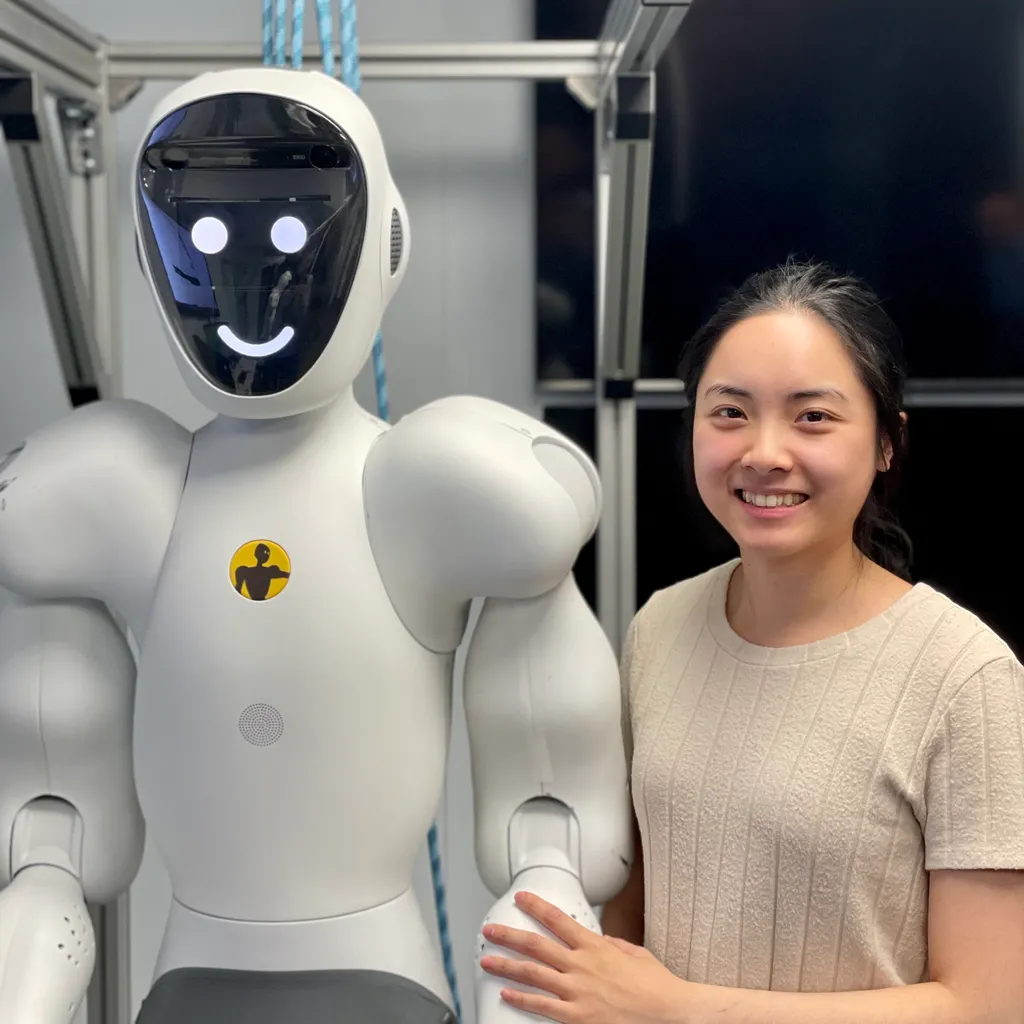 A perception engineer in a lab coat stands beside a white-and-black humanoid collaborative robot in a research lab, adjusting its arm at a workstation.